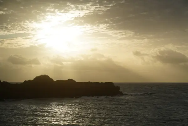 Hazy sun low over a dark headland