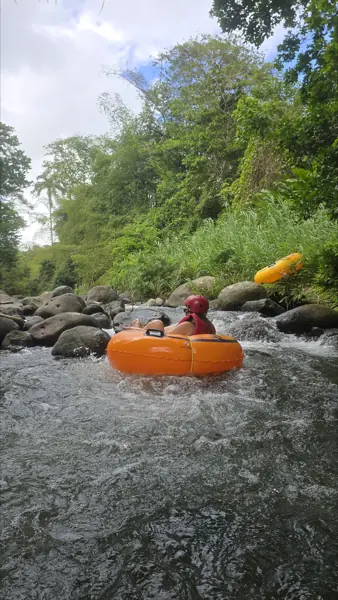 A river tuber riding through whitewater between boulders