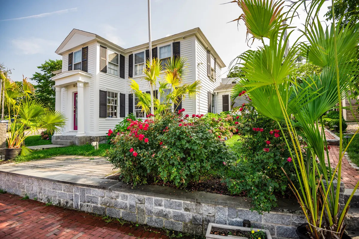 The white clapboard bed and breakfast with its red door, behind flowering rose beds