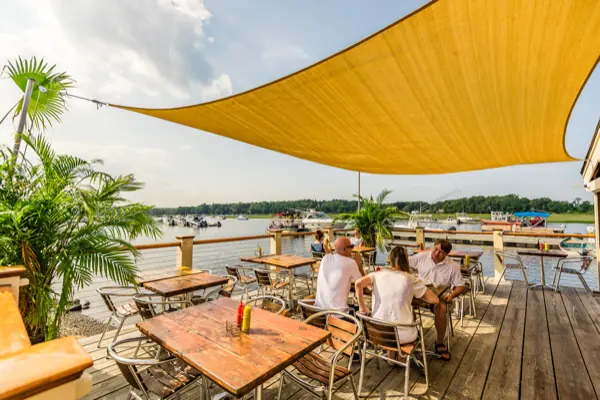 Deck tables under the yellow shade sail at the Boathouse Bar
