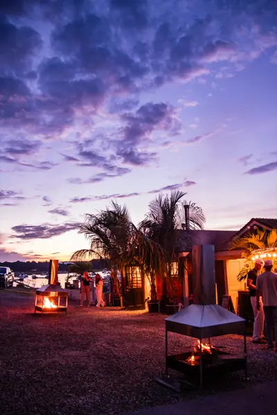 Fire pits burning on the gravel terrace under a purple dusk sky