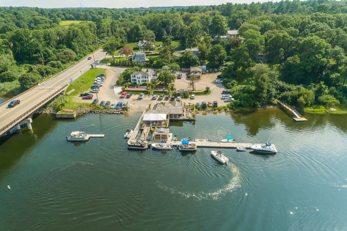 A boat cutting a wake through the channel past the marina, seen from above