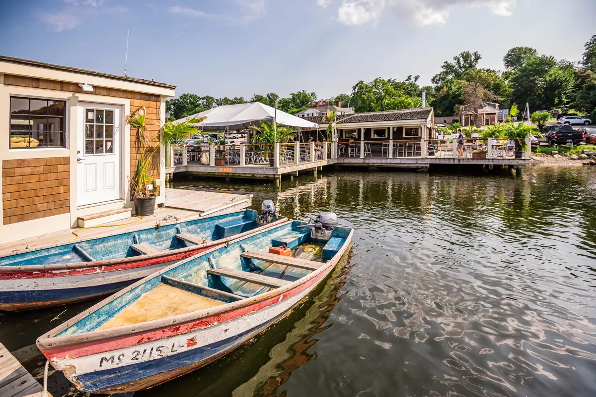 Two painted wooden skiffs tied alongside the dock with the boathouse behind